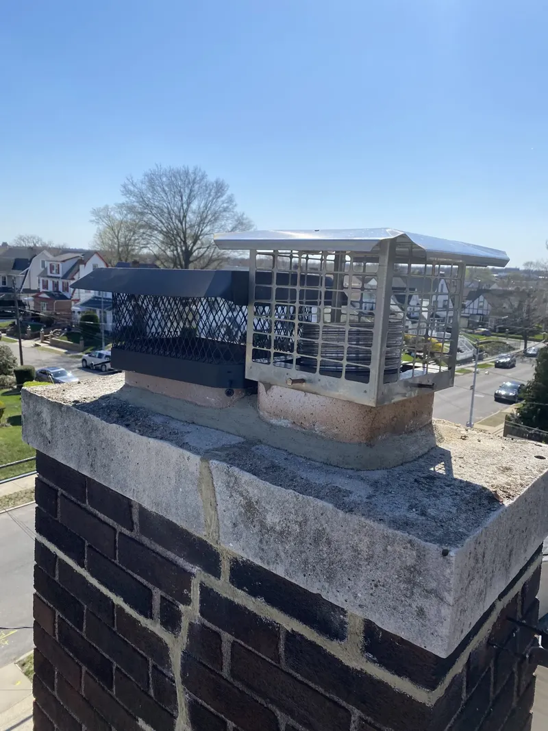 Chimney with a stainless steel cap on a flat city roof