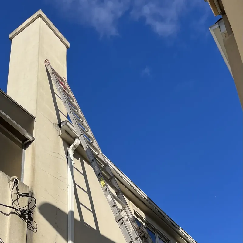 Tall chimney on a building, with a ladder against it