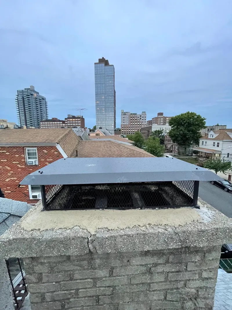 Extended chimney with a cap on a city roof, with the skyline behind