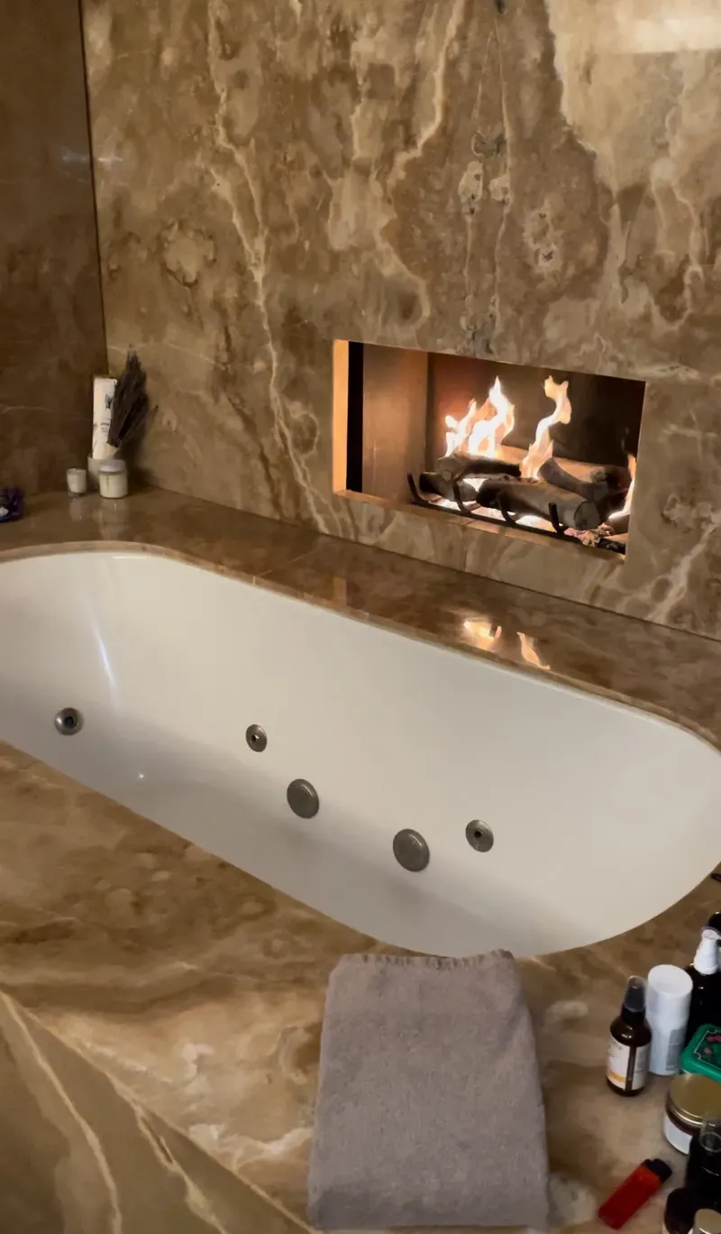 Gas fireplace set in a marble wall above a bathtub