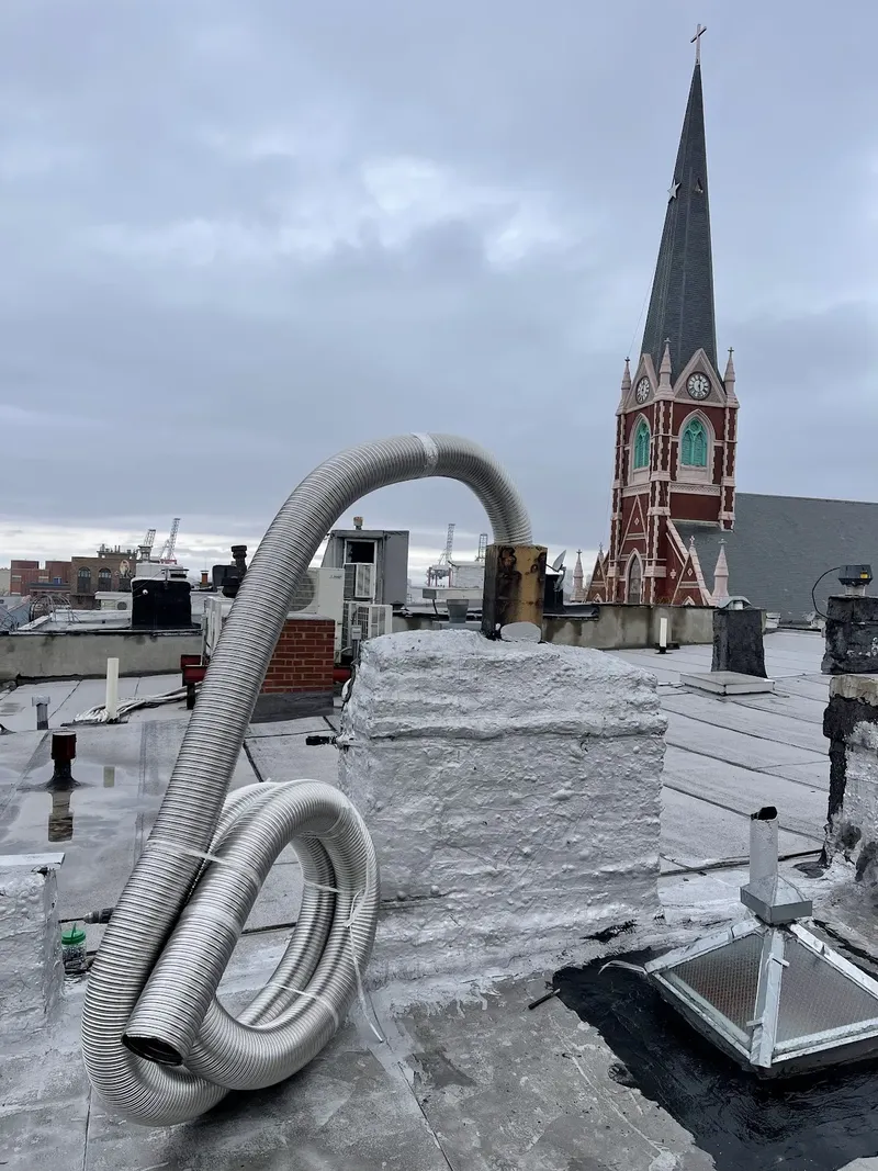 Stainless steel liner on a rooftop, with a church steeple behind