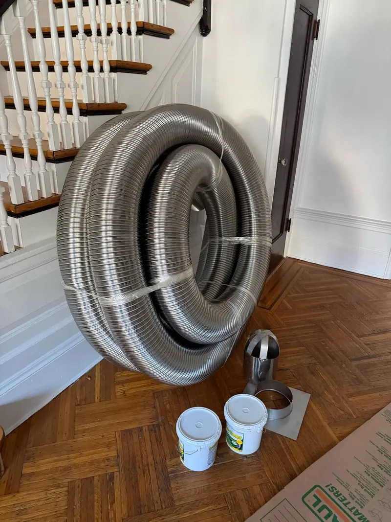 Coil of stainless steel chimney liner in a row house hallway