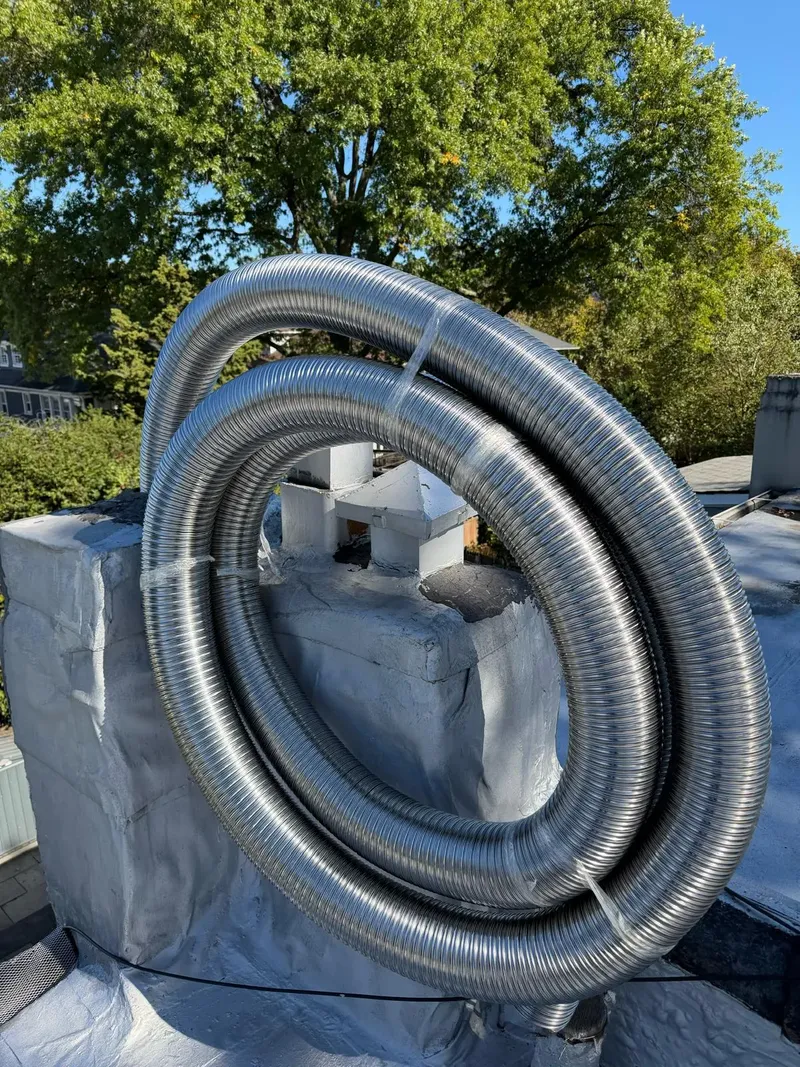 Coil of stainless steel chimney liner on a rooftop, ready to go into the chimney