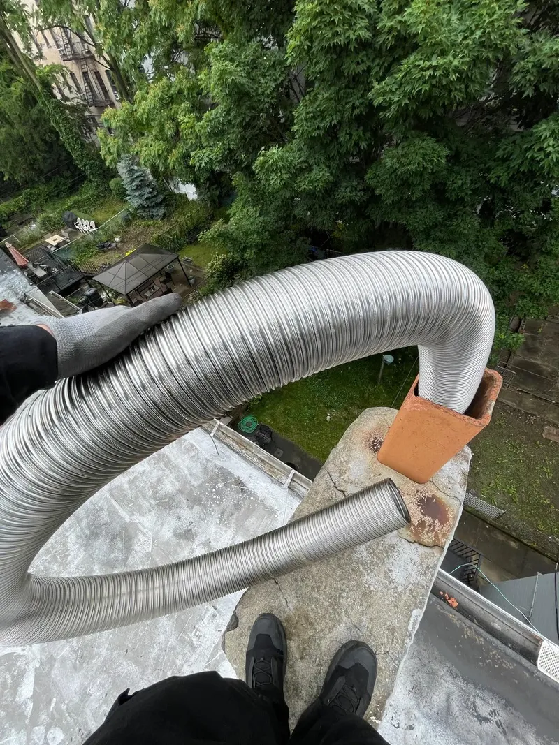 Stainless steel liner being fed into a chimney on a rooftop