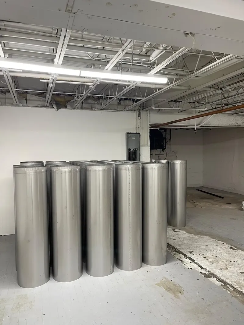 Sections of stainless steel vent pipe standing in a basement