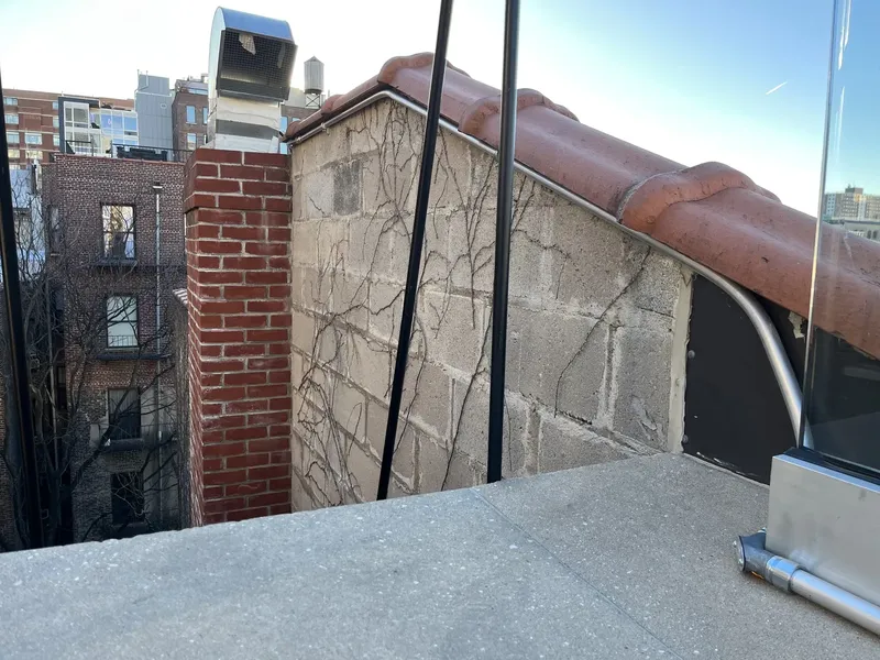 Brick chimney beside a rooftop wall
