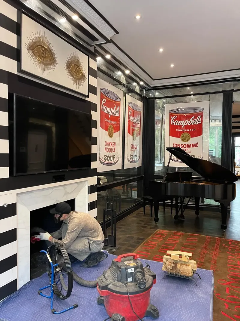 Technician cleaning a fireplace in a living room