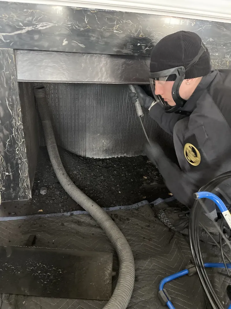 Technician sweeping a fireplace flue with a rotary brush