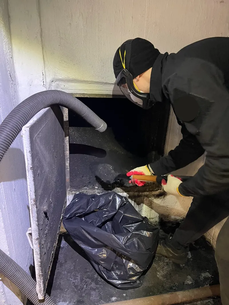 Technician cleaning inside a fireplace opening