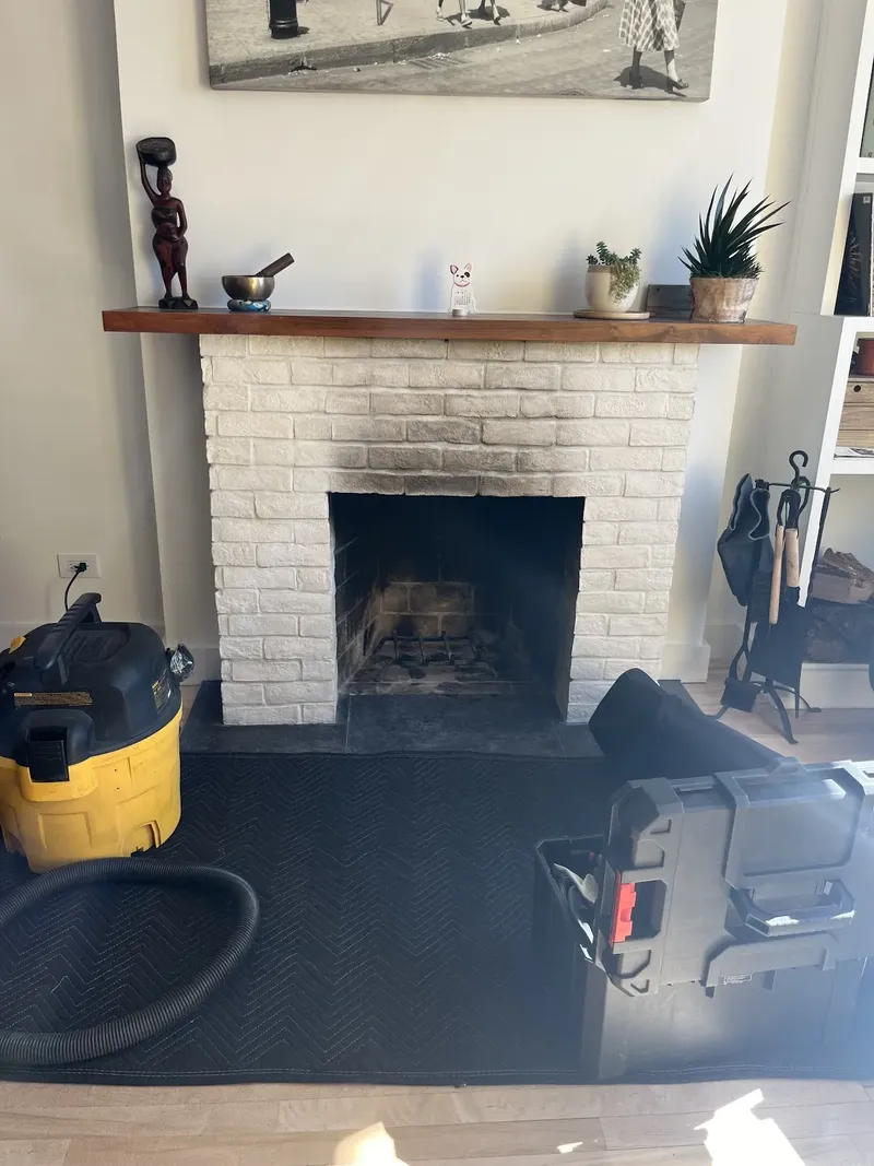 Drop cloth and vacuum set up in front of a white brick fireplace