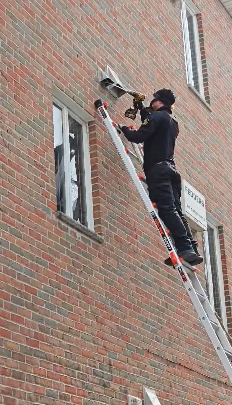 Technician on a ladder against a brick building